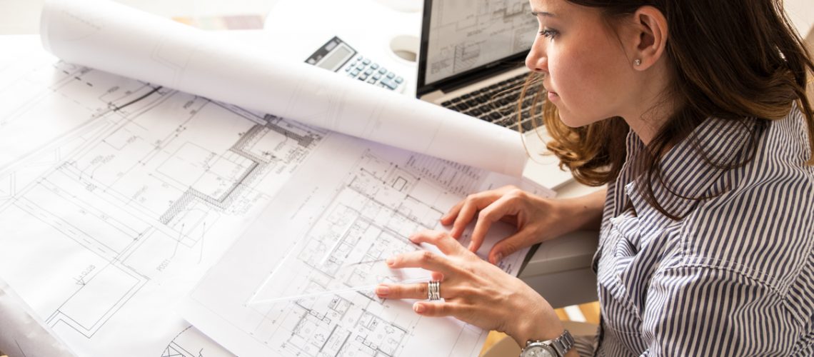 Female architect working at home.She looking at blueprint.